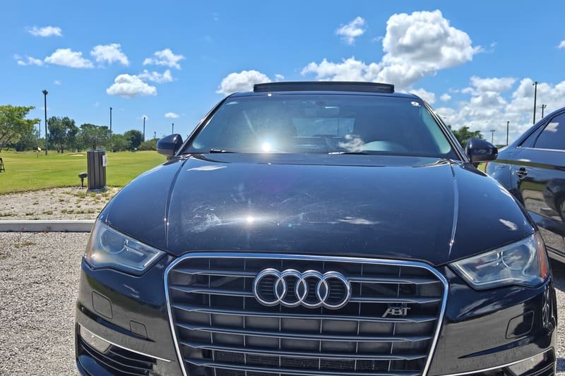 El Audi A3 negro con kit ABT de Grupo Fullequipe, de frente, con el emblema ABT en la parrilla